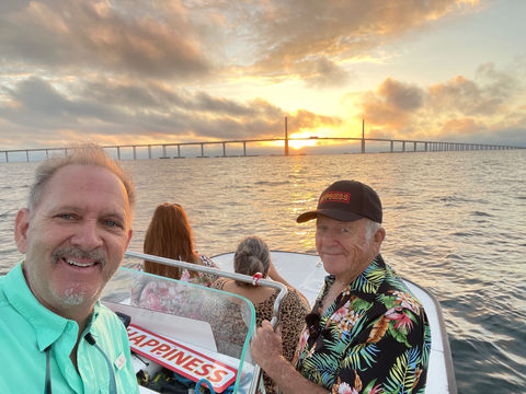 Gary King on a boat at sunset with the Sunshine Skyway Bridge spanning the horizon behind him
